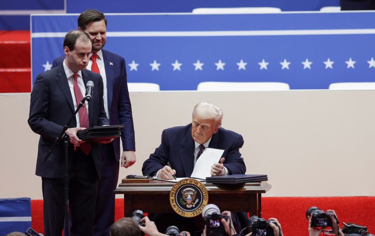 U.S. President Donald Trump signs executive orders as U.S. Vice President J.D. Vance looks on during a rally on the inauguration day of his second Presidential term, inside Capital One, in Washington, U.S. January 20, 2025. Reuters/Mike Segar/Proibida reprodução