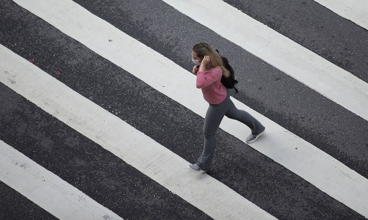 Mulher com máscara de proteção em avenida de São Paulo