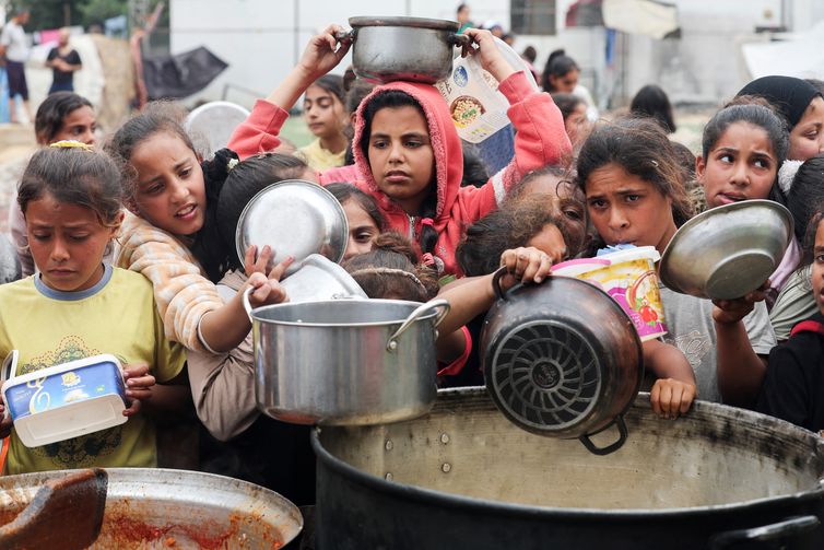 Palestinos aguardam para receber comida preparada por uma cozinha comunitária, em Nuseirat, Faixa de Gaza
08/04/2025
REUTERS/Ramadan Abed