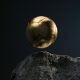 a golden soccer ball sitting on top of a rock