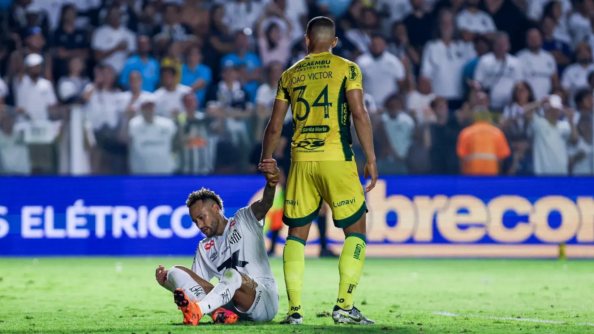 Joao Victor of Mirassol helps Neymar Junior of Santos get up.
