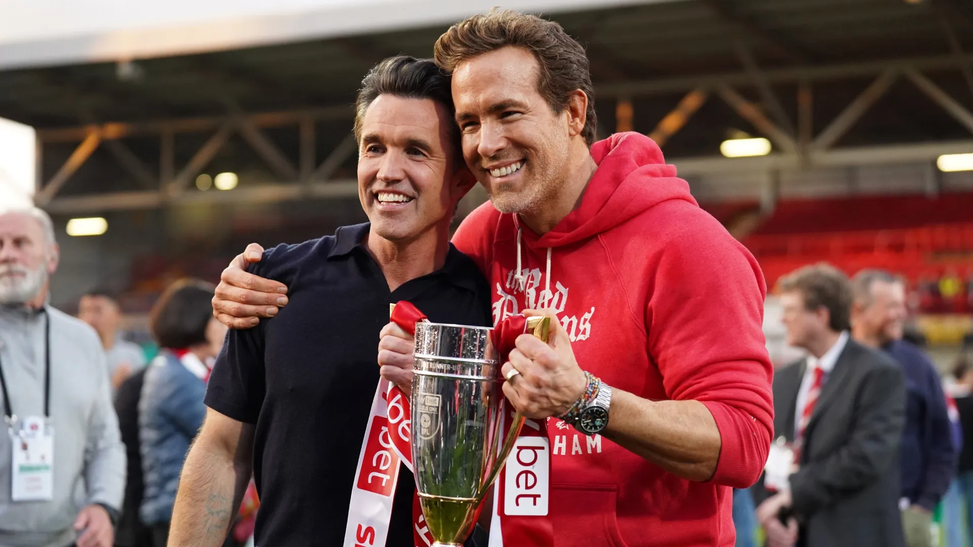 Rob McElhenney e Ryan Reynolds, coproprietários do Wrexham AFC, posam para uma foto com o troféu da EFL League One.