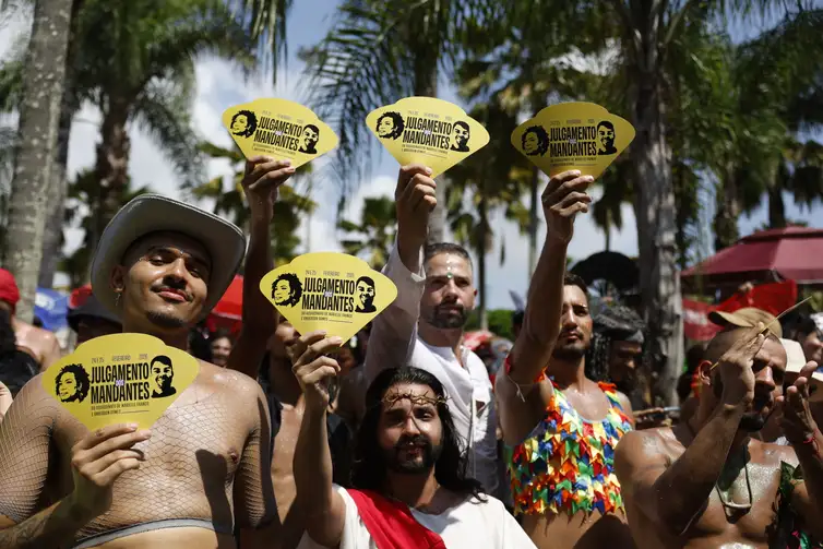 Rio de Janeiro (RJ), 15/02/2026 – Foliões recebem leques alusivos ao julgamento dos mandantes do assassitato de Marielle Franco e Anderson Gomes no bloco Divinas Tretas, que atrai público LGBTQIAPN+ no Aterro do Flamengo. Foto: Fernando Frazão/Agência Brasil