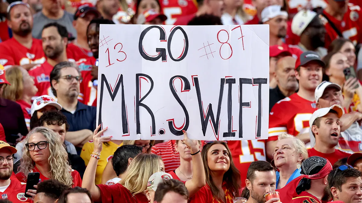 A fan holding a sign that says Go Mr. Swift at an NFL game.