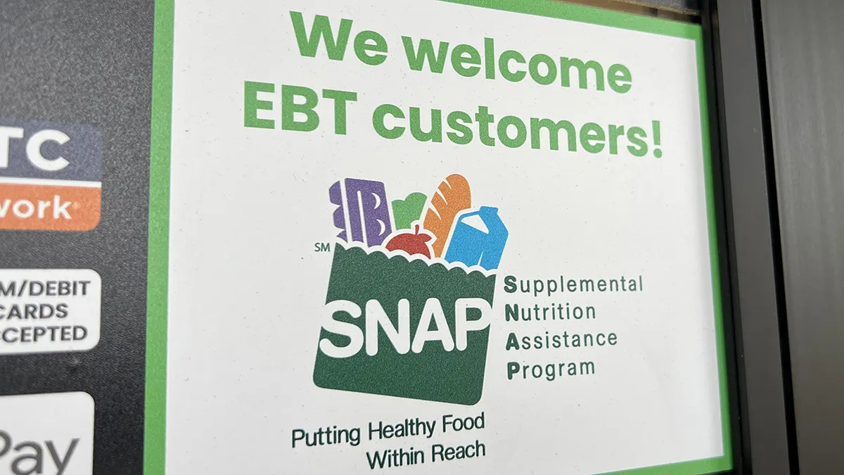 A sign at a supermarket entrance reading We Welcome EBT customers with a SNAP logo