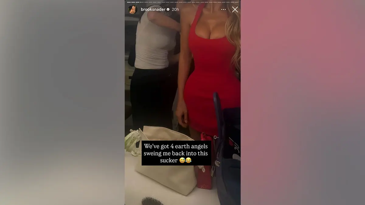 Nader in a red dress with someone behind her sewing her into her dress in May 2026.
