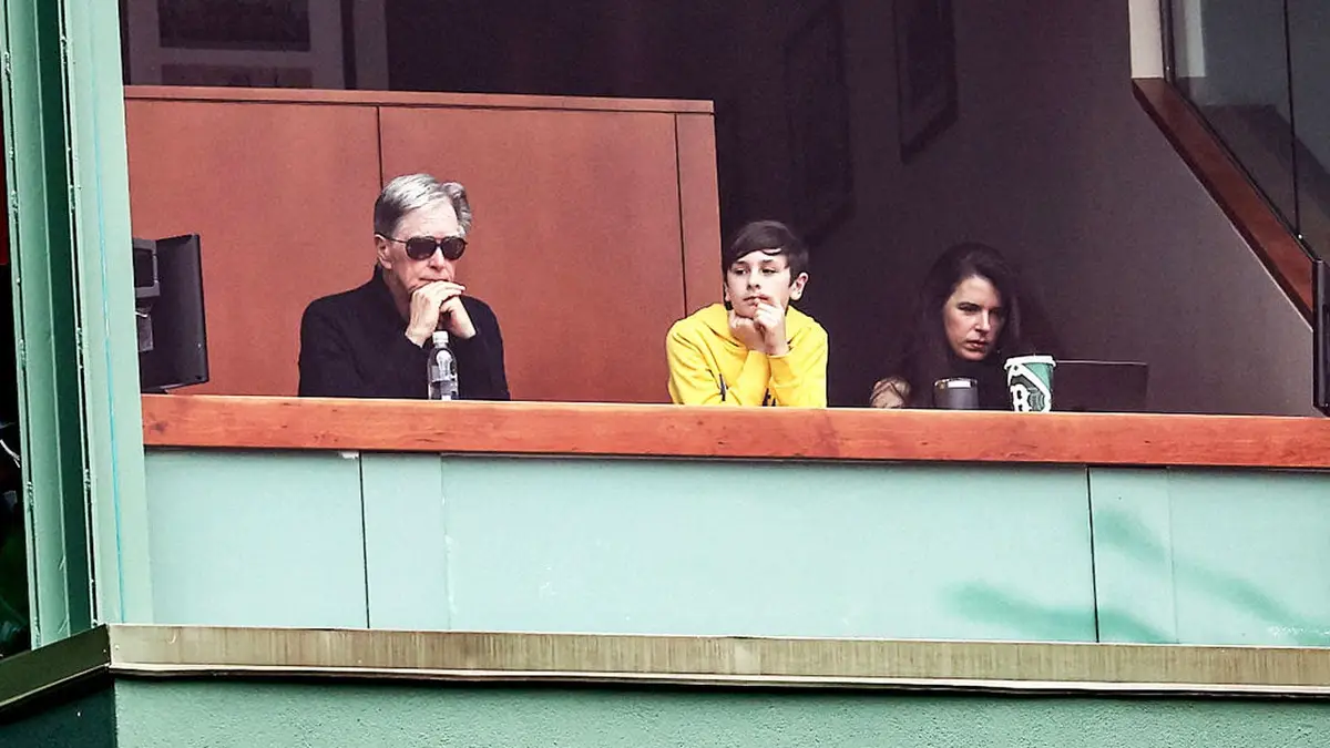 John Henry watching a baseball game at Fenway Park with his wife Linda Pizzuti Henry and her son Xander