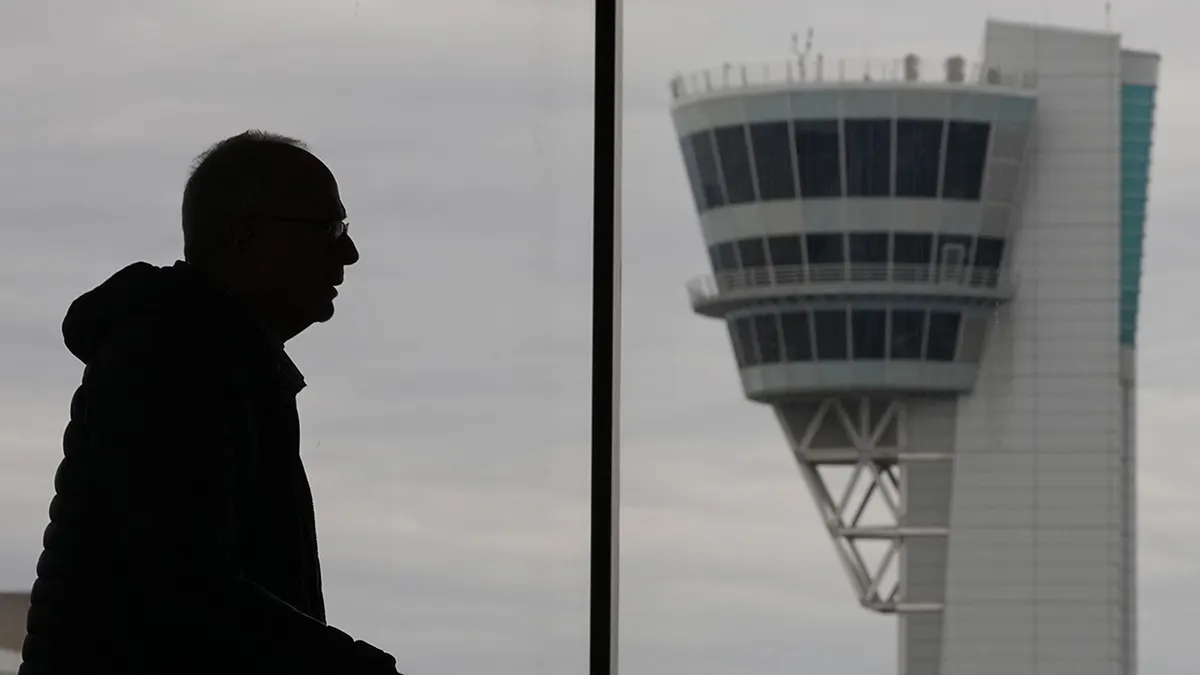 A traveler walking near an air traffic control tower at Philadelphia International Airport