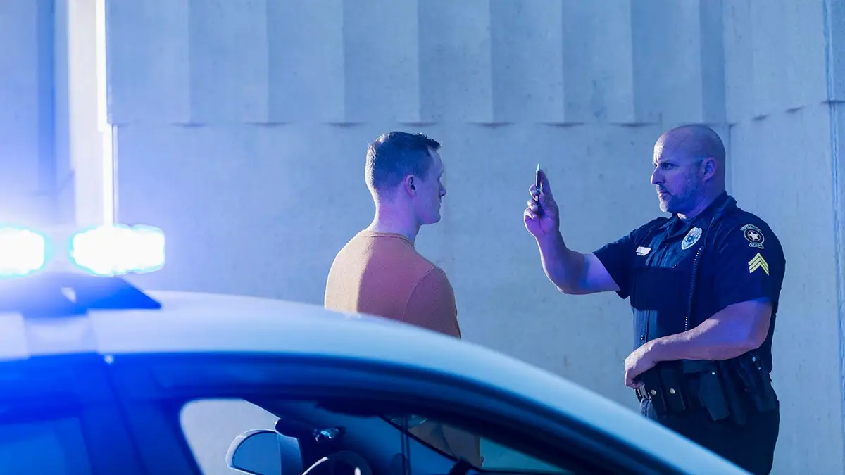 Police officer giving sobriety test to young man outdoors