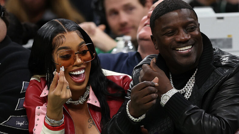 O músico Akon e sua esposa Amirah-Iman Thiam riem durante um jogo