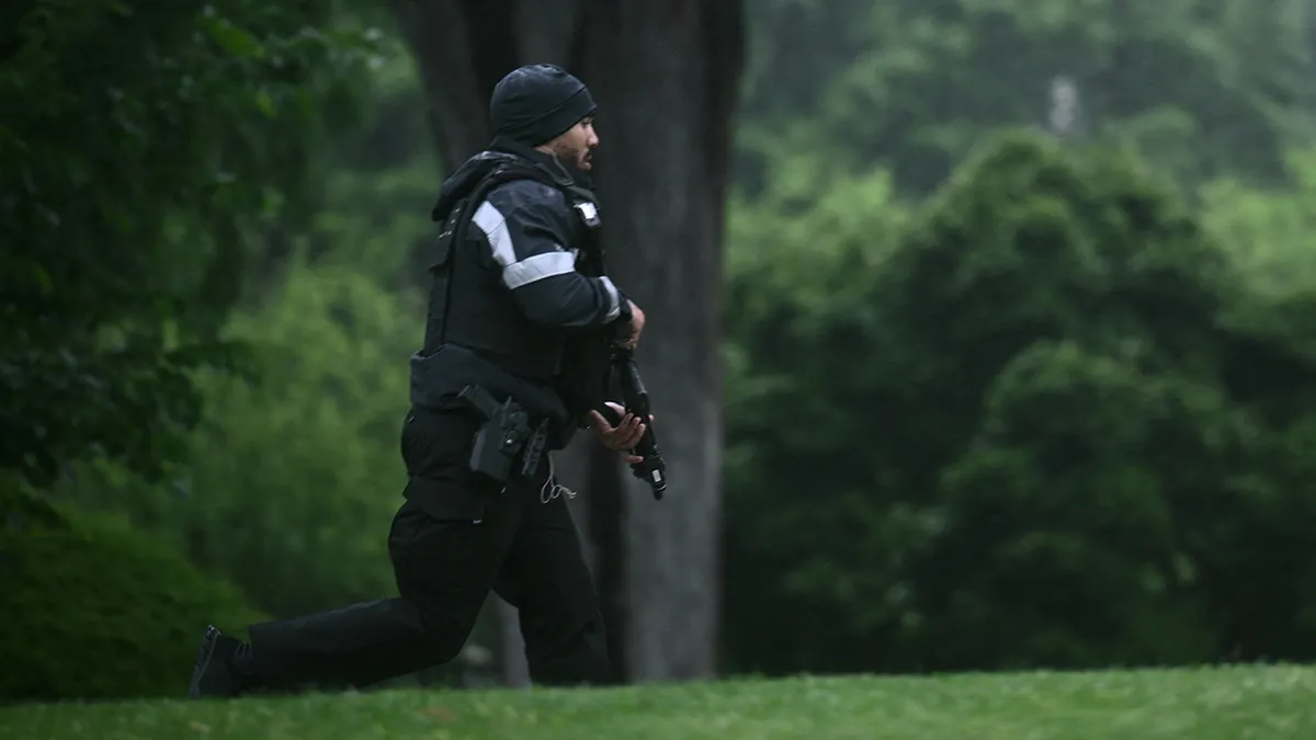 An armed Secret Service agent reacts at the White House