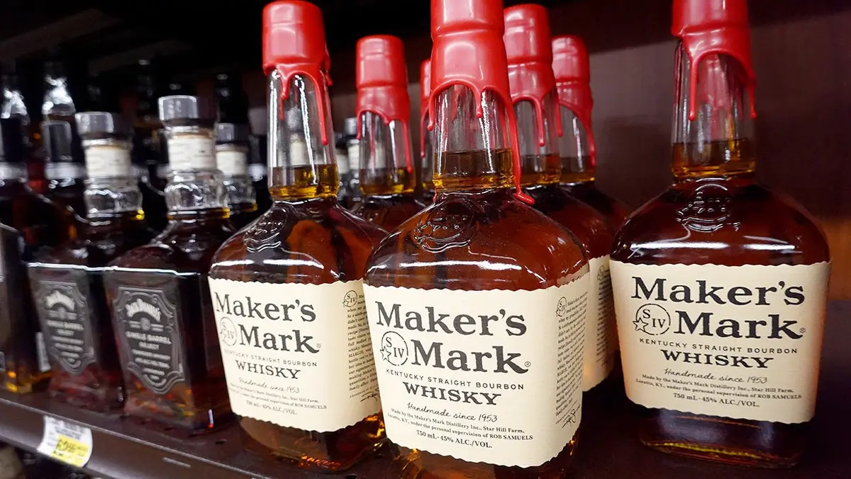 Bottle of Maker's Mark whisky sit on a shelf.