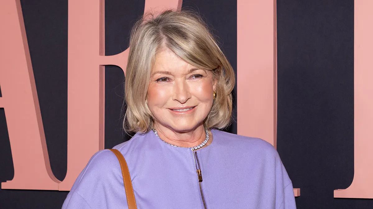 Martha Stewart wearing a lavender zip-front top and gold earrings at a formal event