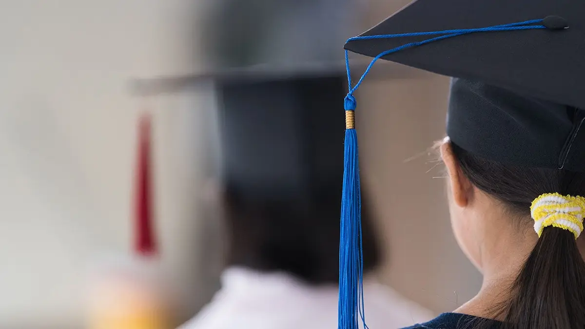 Asian female school graduate wearing a graduation cap holding a rolled certificate