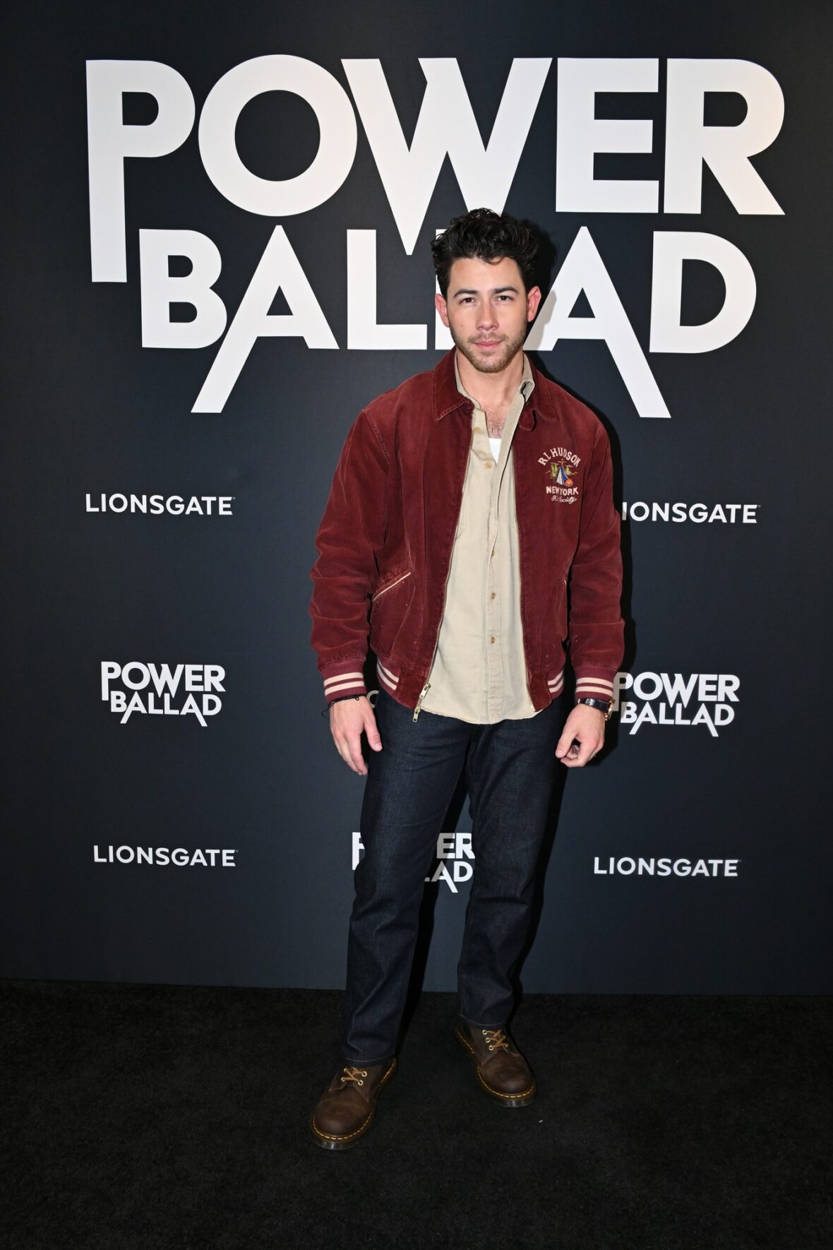 Nick Jonas usa jaqueta bomber cor de vinho para sessão fotográfica de exibição do POWER BALLAD