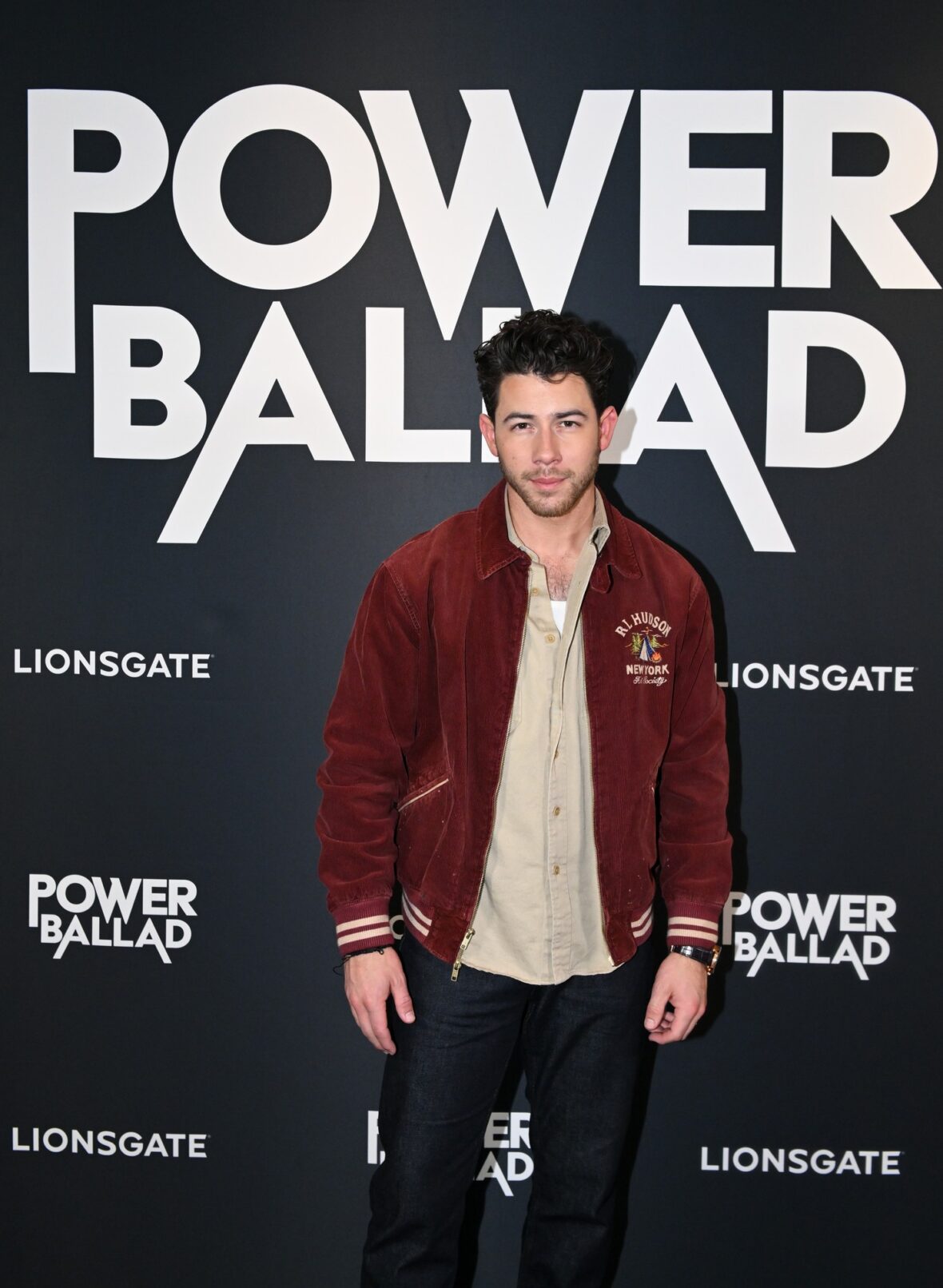 Nick Jonas usa jaqueta bomber cor de vinho para sessão fotográfica de exibição do POWER BALLAD