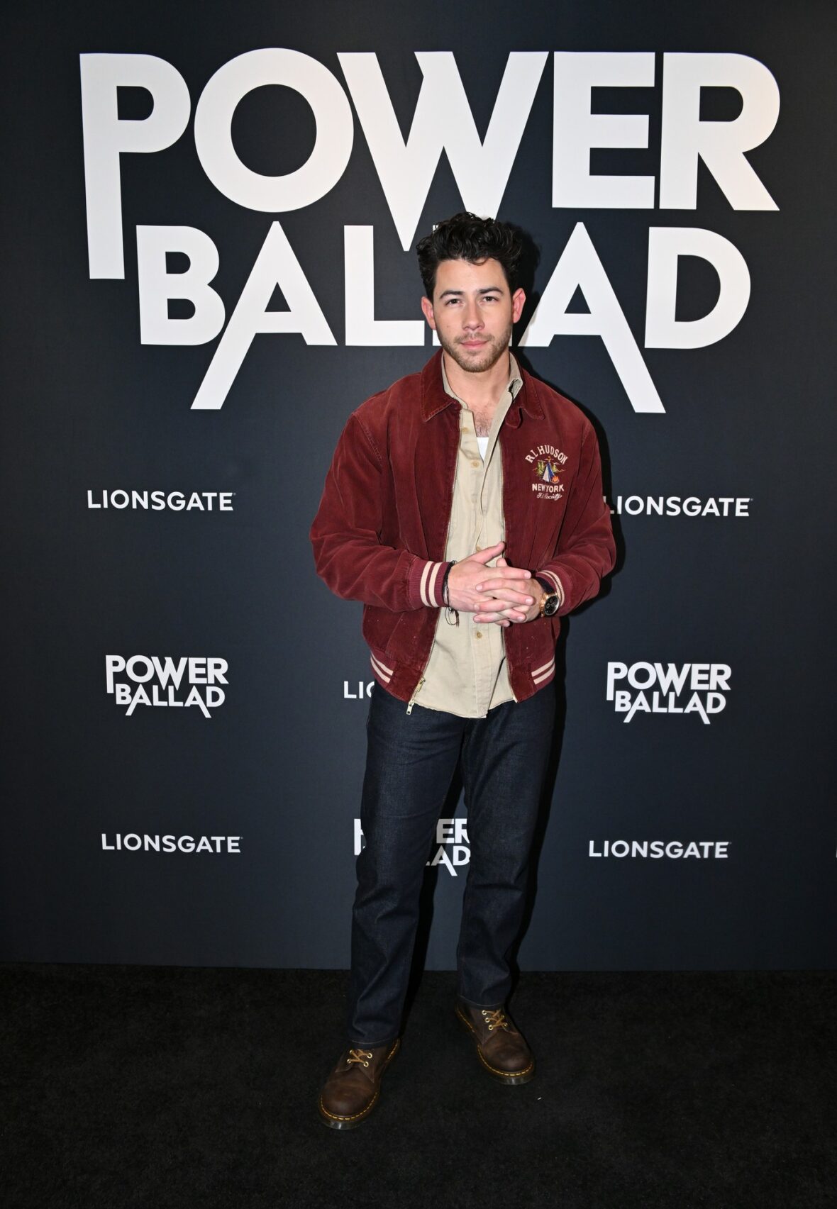 Nick Jonas usa jaqueta bomber cor de vinho para sessão fotográfica de exibição do POWER BALLAD