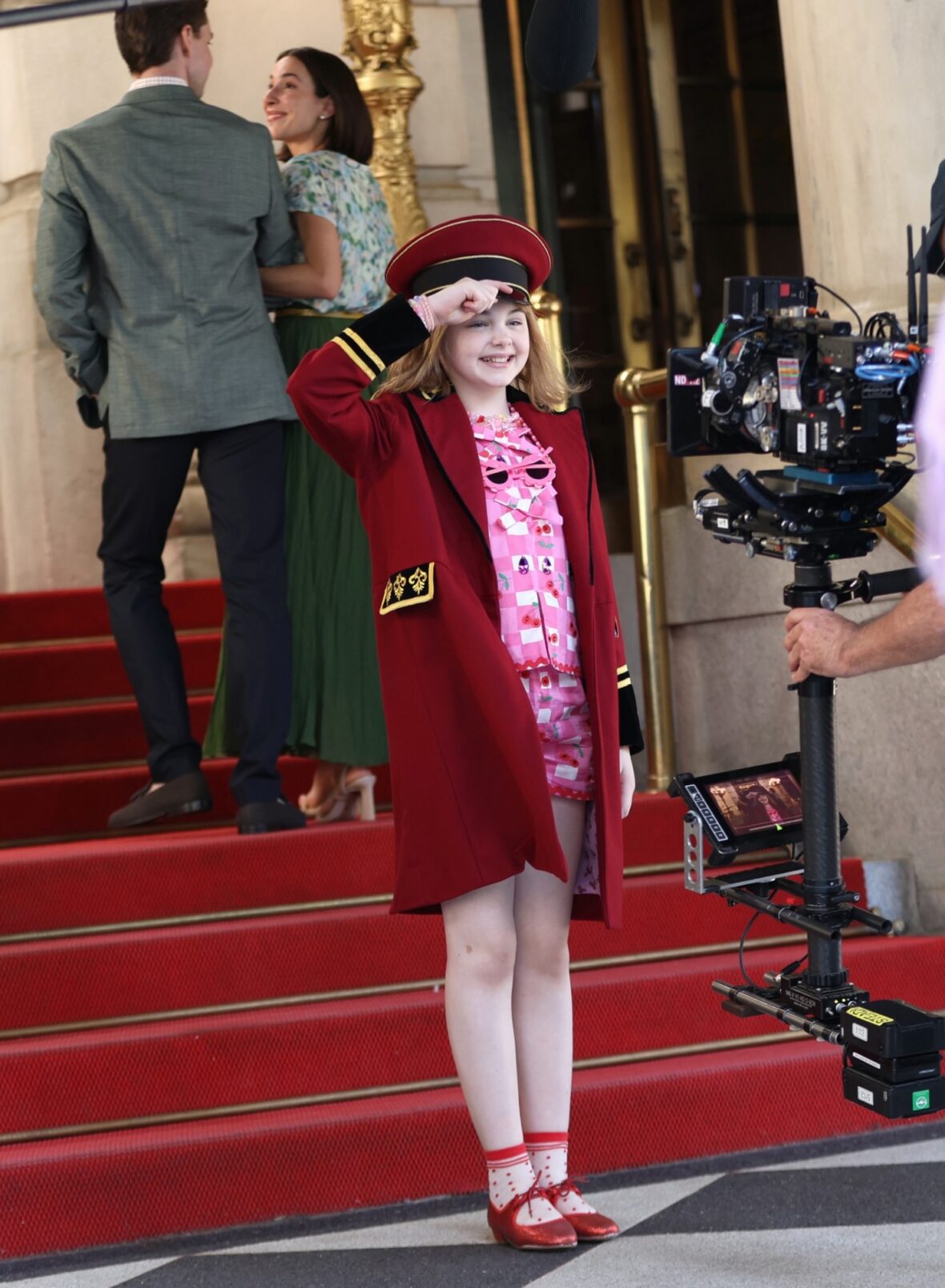 Mae Schenk usa um conjunto vermelho para filmar cenas fora do Plaza Hotel para ELOISE