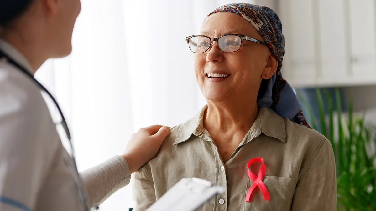 A cancer survivor smiles at a doctor in a doctor's office.