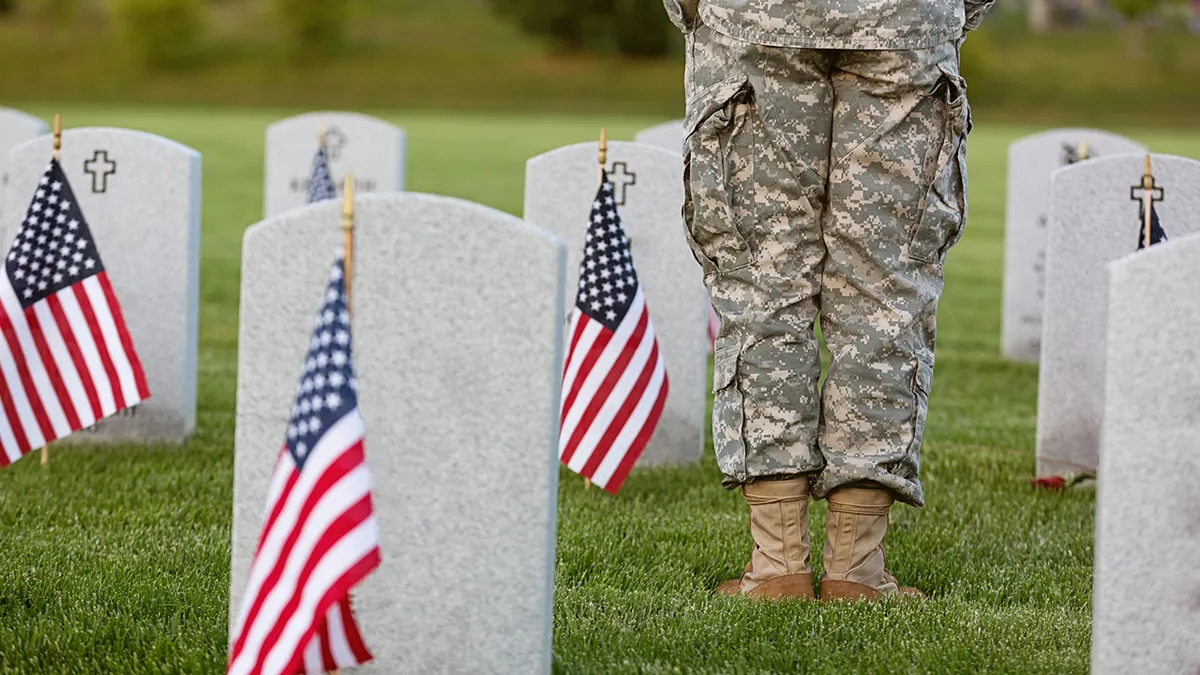 American soldier in uniform standing at a cemetery memorial
