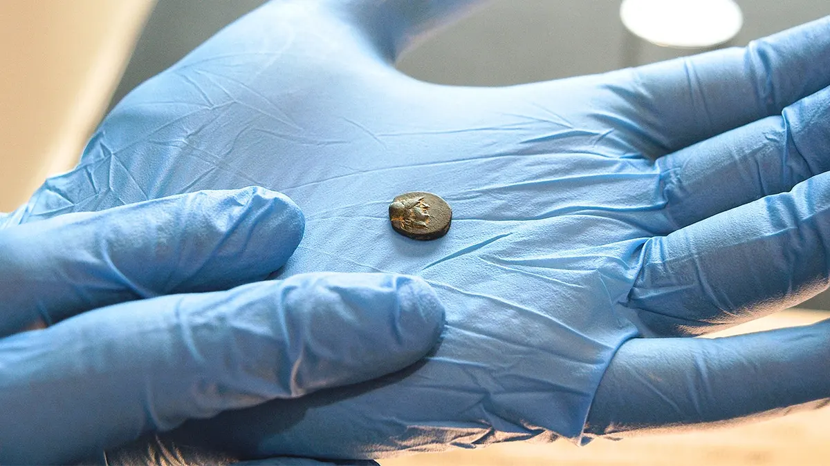 Man holding small coin with glove