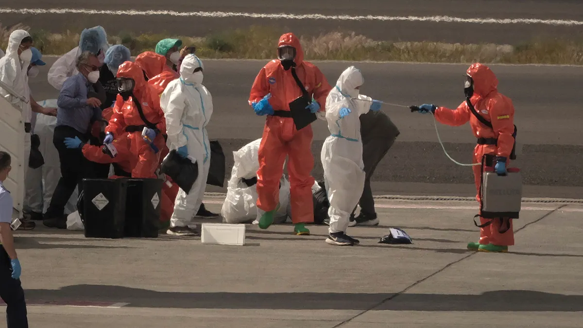 Spanish government officials spraying disinfectant on passengers at Tenerife airport