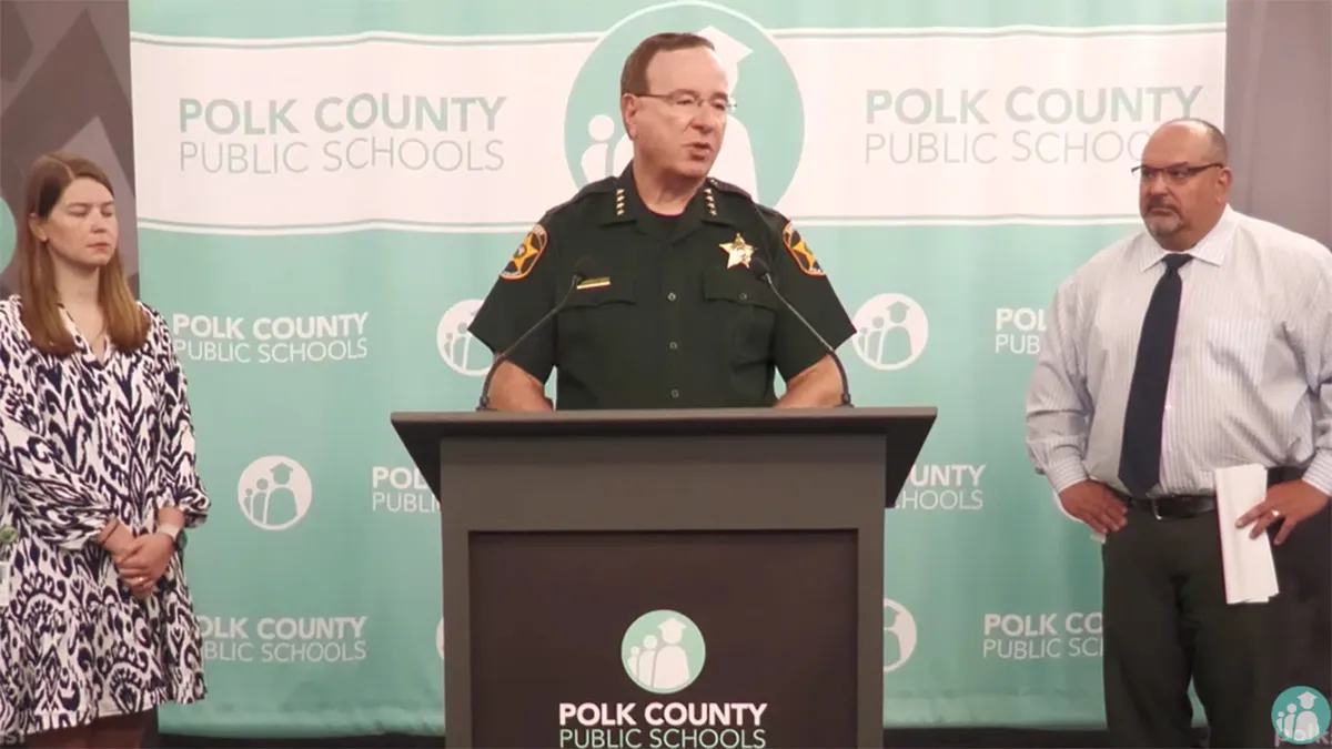 Polk County Sheriff Grady Judd and Superintendent Fred Heid speaking at a podium