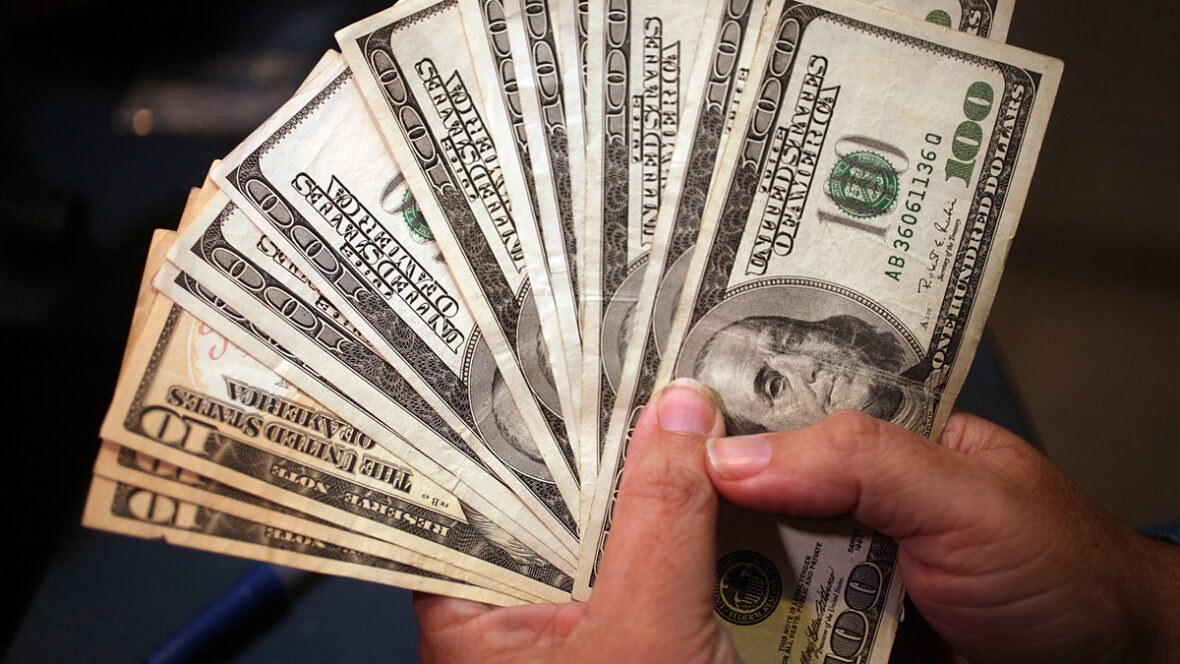 Uma pessoa segurando uma pilha de notas de US$ 100