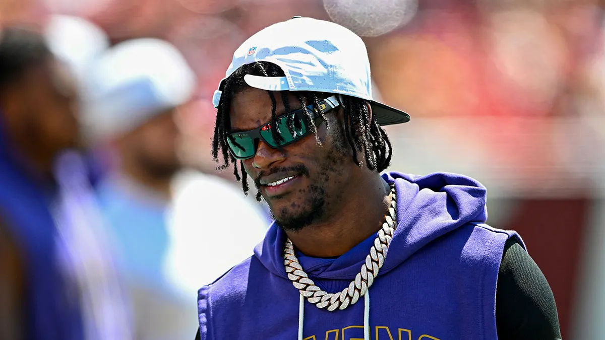 Lamar Jackson wearing number 8 jersey watches NFL preseason game on field