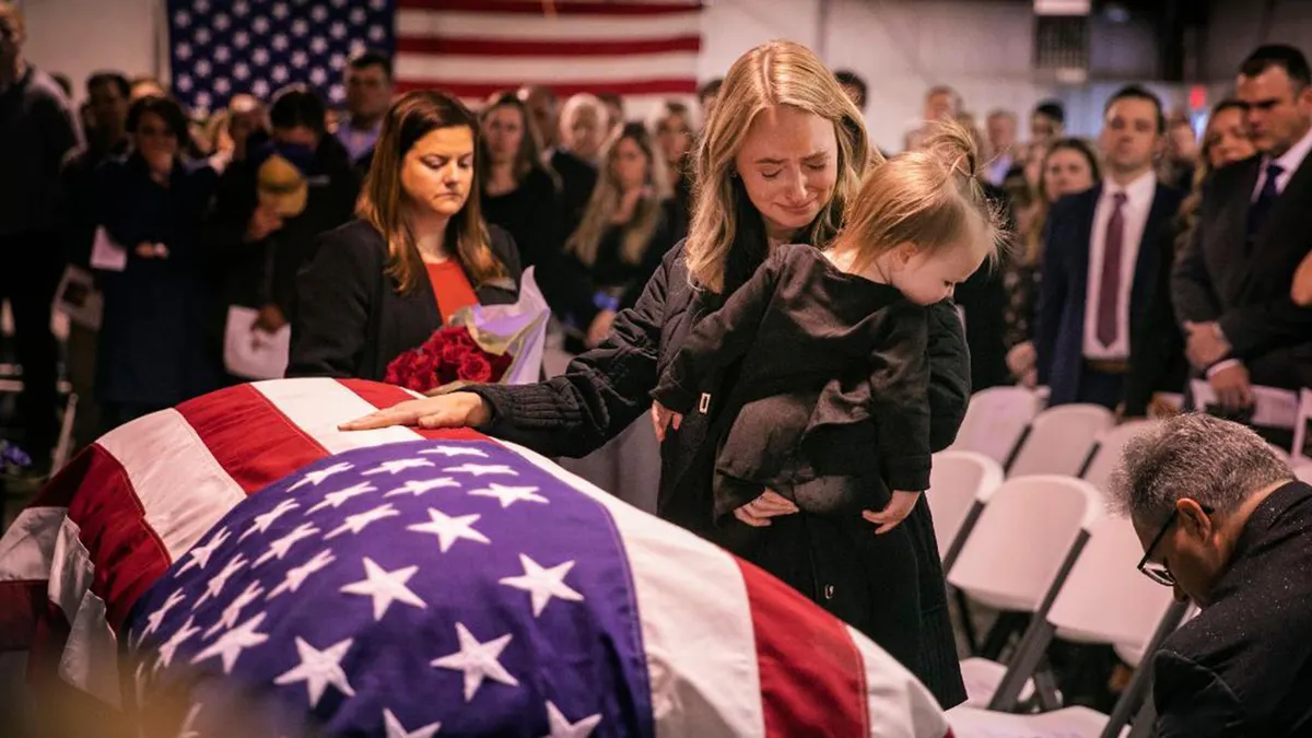 Amy King with her daughter, Adalyn. She has her hand on a casket of her late husband