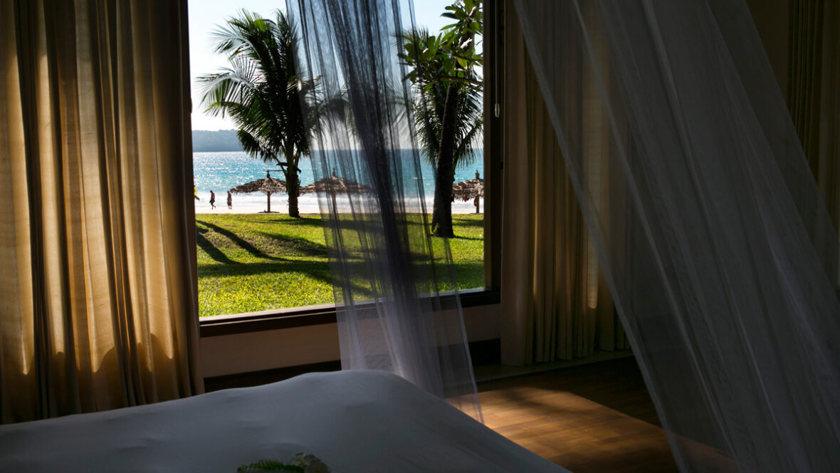 Imagem stock de um quarto de hotel com vista para uma praia.