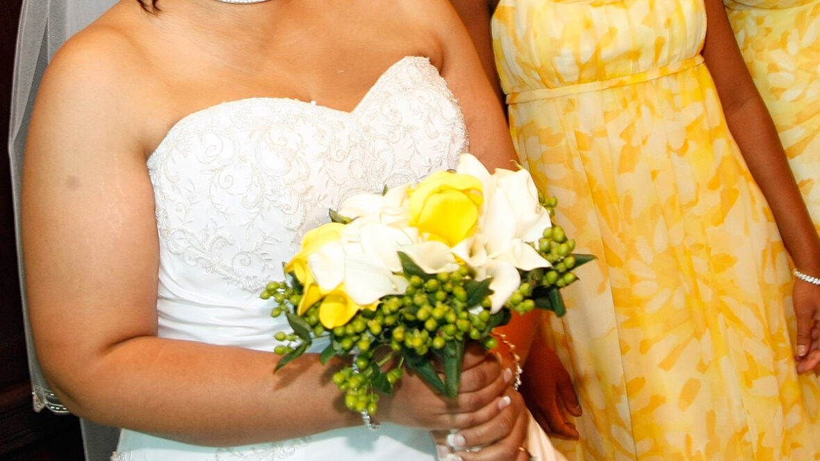 Imagem de uma noiva segurando seu buquê ao lado de sua dama de honra em amarelo