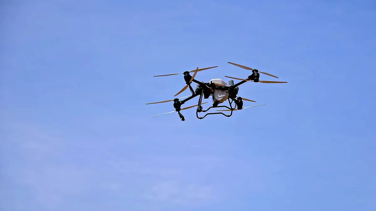 A drone flying in the sky carrying a payload