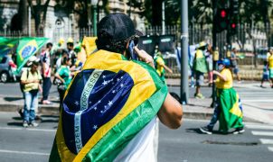 a man with a flag on his back walking down the street