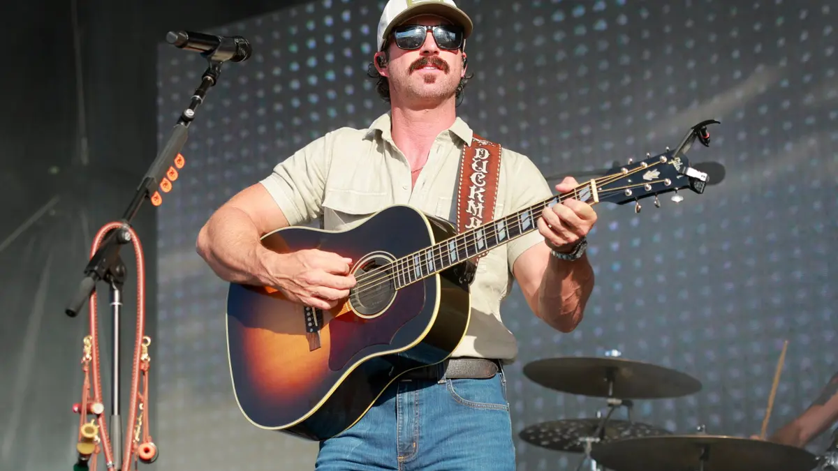 Riley Green singing and playing guitar on stage at a music event in Nashville