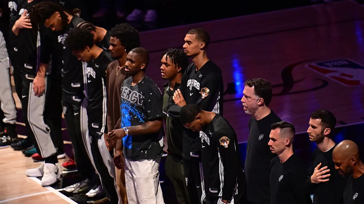 Victor Wembanyama standing with San Antonio Spurs teammates during the National Anthem at Frost Bank Center