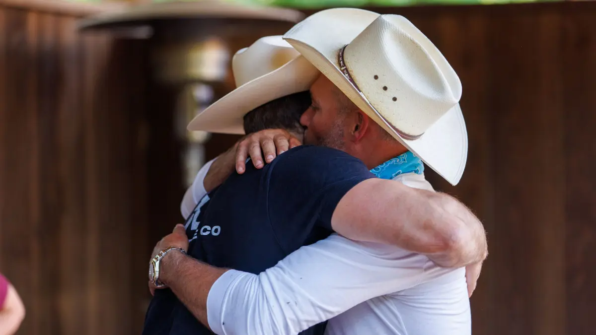 Steven McBee Jr. hugging his father Steve McBee in a studio setting