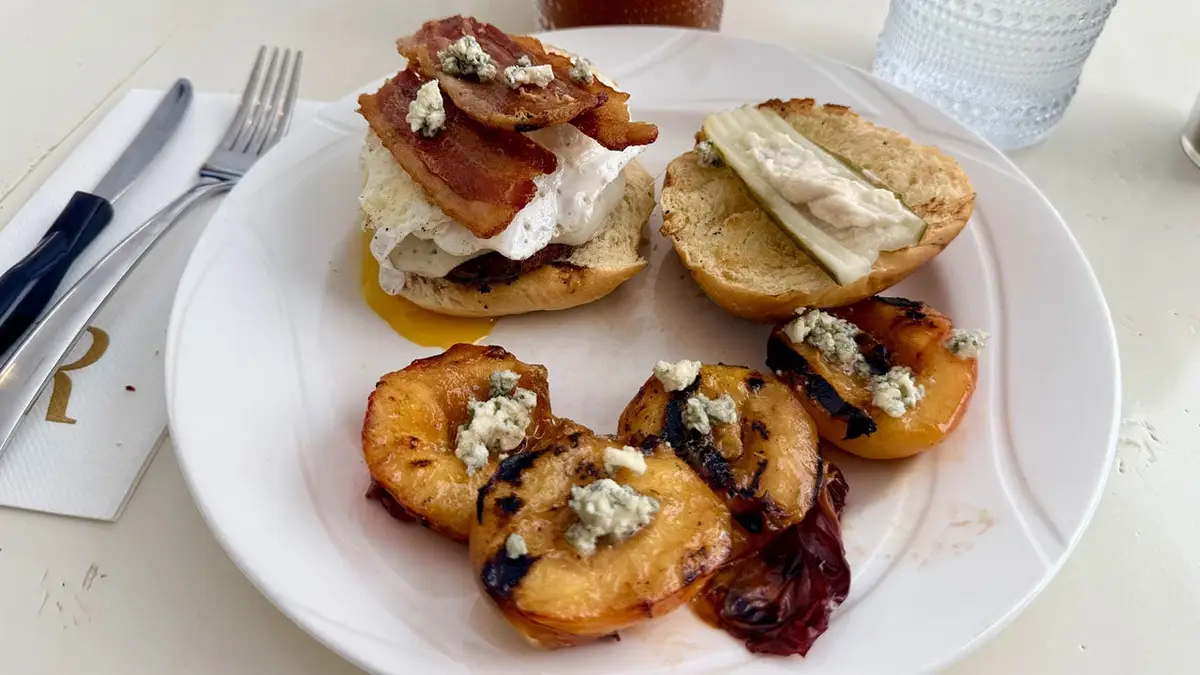 Havarti brunch burgers off the grill, topped with an egg, hickory smoked bacon and blue cheese crumbles on toasted rolls with pickle + horseradish garnish. Grilled peaches brushed with Basil Hayden Toast, brown sugar and wagyu tallow glaze, also finished with blue cheese crumbles.