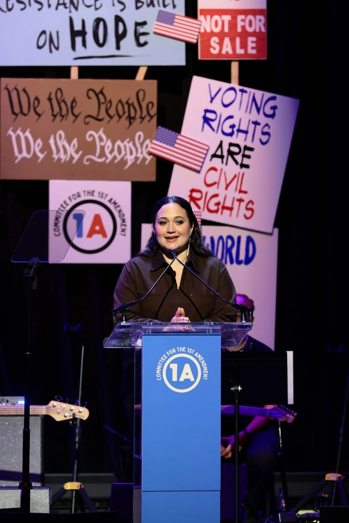 Lily Gladstone fala no palco durante Rise Up, Sing Out: Um Concerto para a Primeira Emenda
