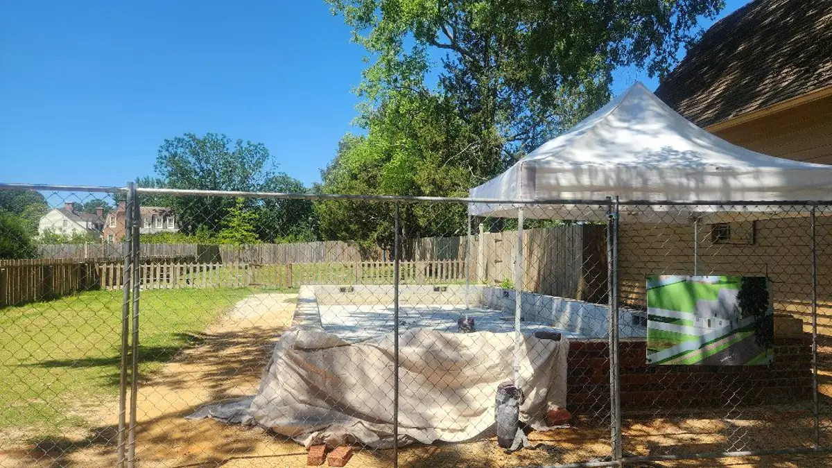 A metal fence is set in front of a yard with a pop-up tent.
