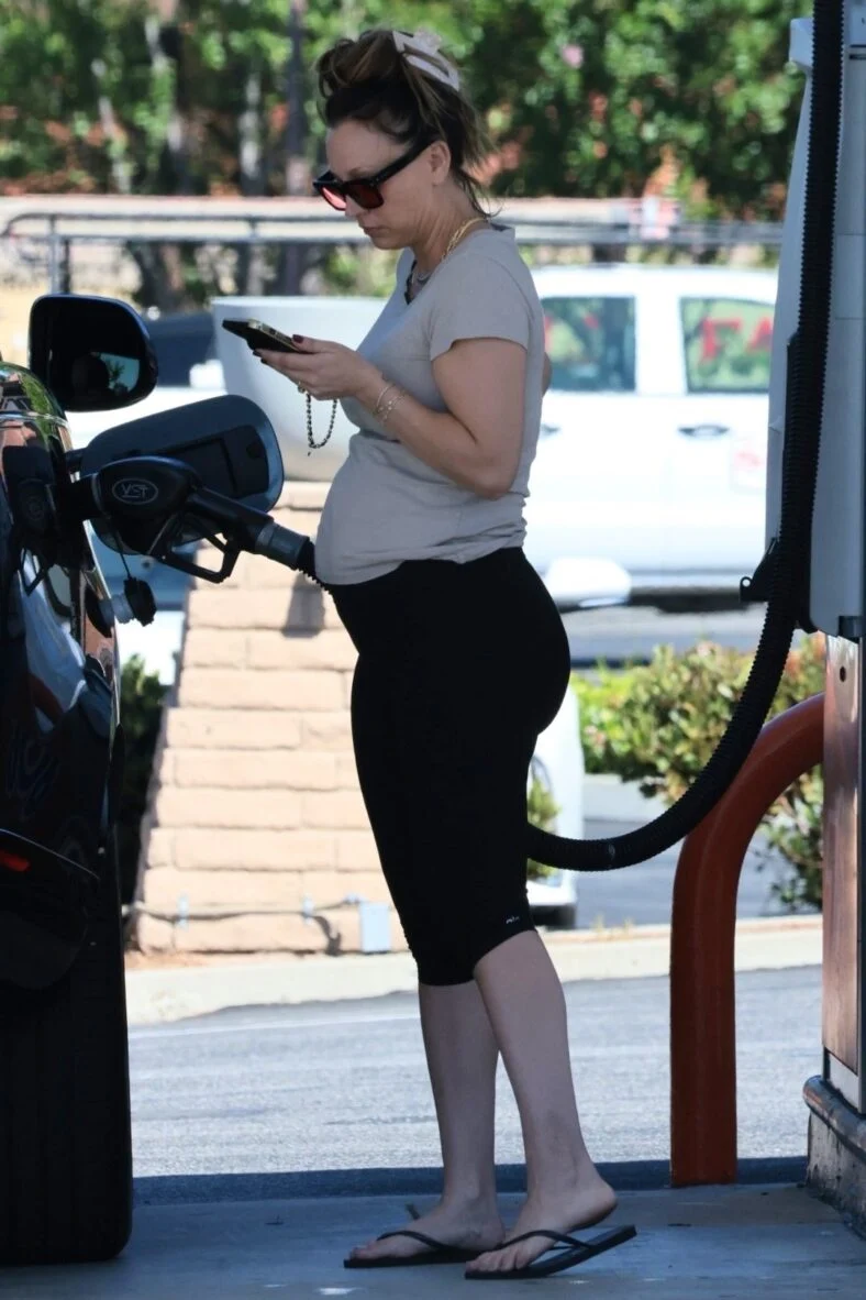 Kaley Cuoco bombeando gasolina enquanto fala no celular