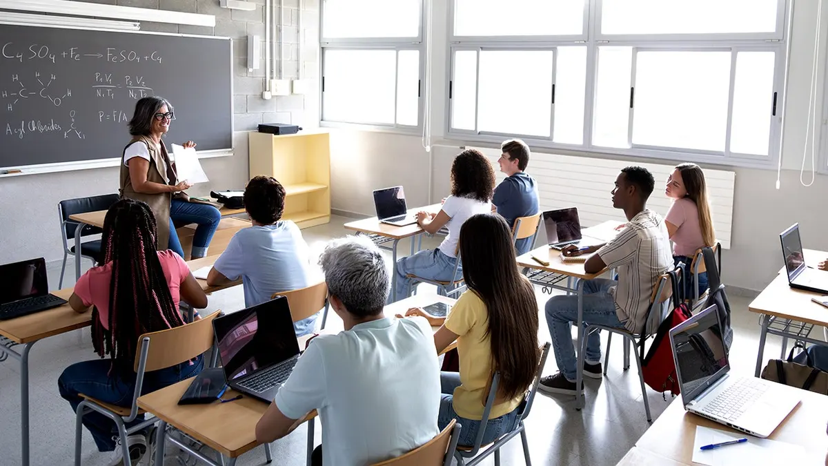 Female teacher explaining lesson to multiracial high school students in classroom