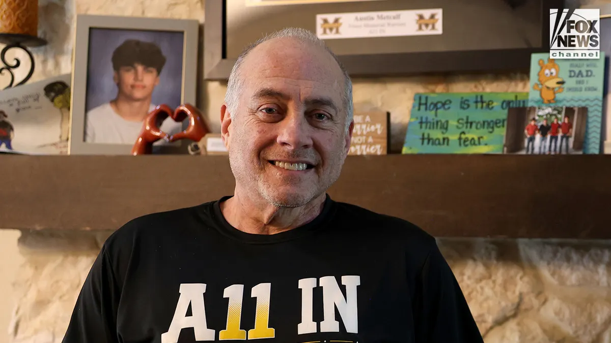 Jeff Metcalf posing with photos of his son Austin Metcalf inside his home during an interview.