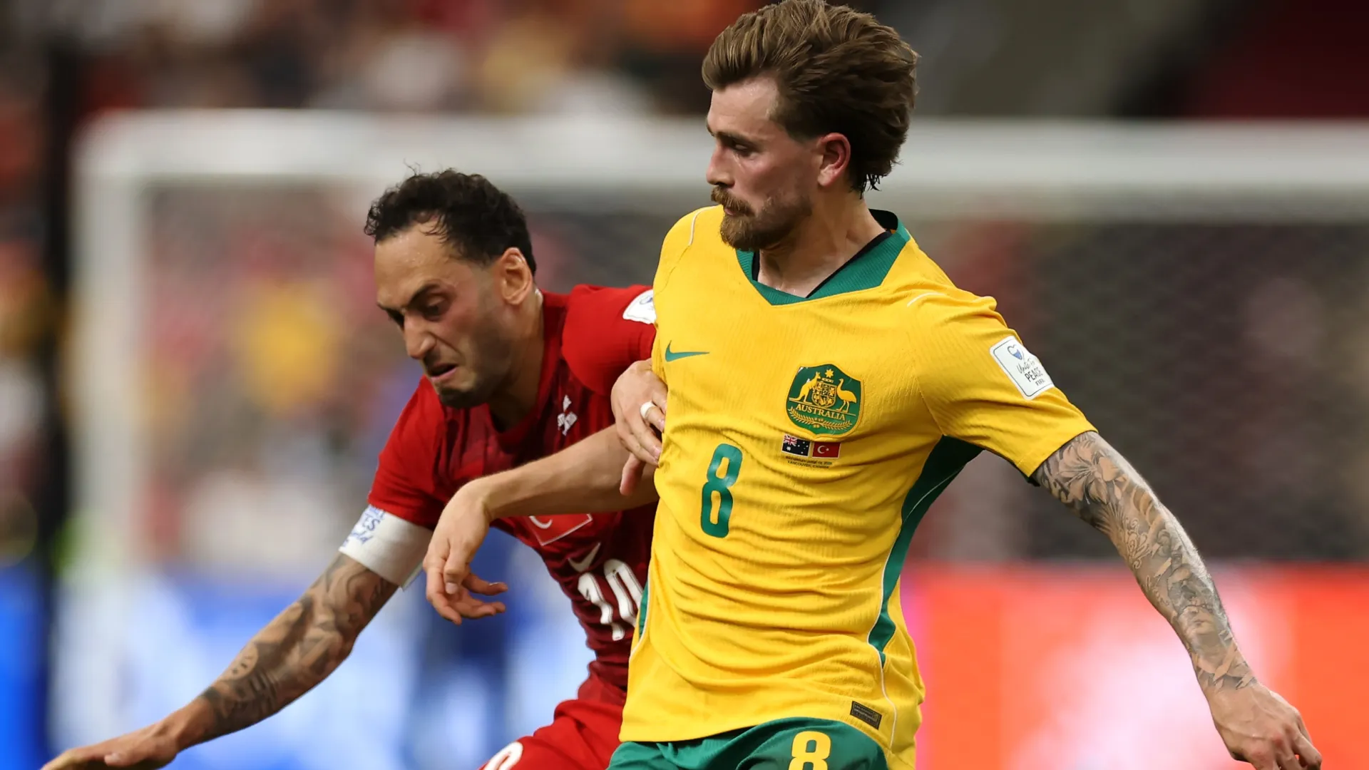Connor Metcalfe, da Austrália, luta pela bola com Hakan Calhanoglu, de Turkiye.