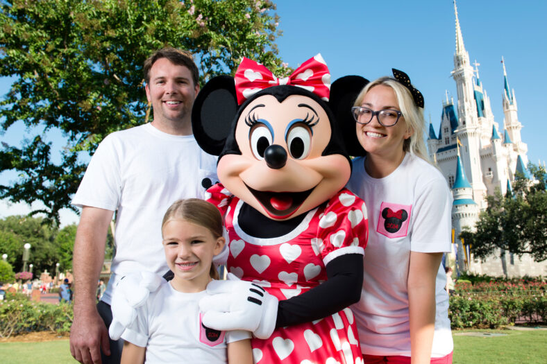Jamie Lynn Spears posa com seu marido, Jamie Watson, sua filha de seis anos Maddie e Minnie Mouse em frente ao Castelo da Cinderela no parque Magic Kingdom em 2014, a família está vestindo camisetas brancas da Disney combinando