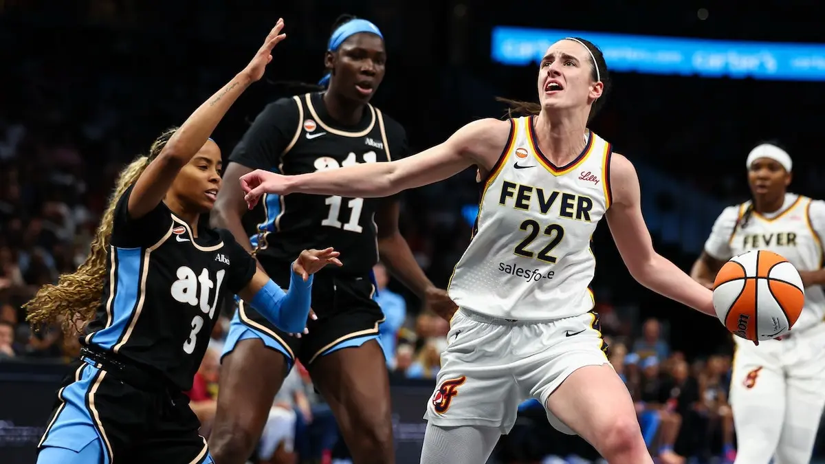 Caitlin Clark of the Indiana Fever drives to the basket against Jordin Canada and Madina Okot of the Atlanta Dream at State Farm Arena
