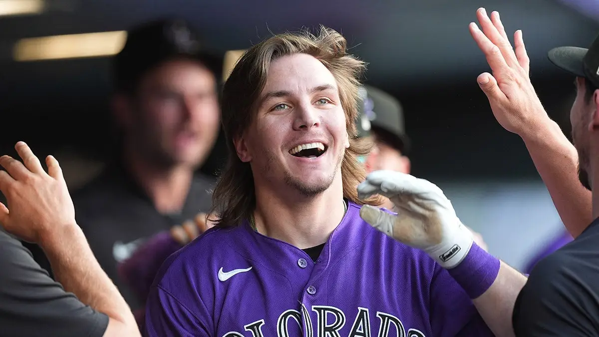 Colorado Rockies' Jake McCarthy returning to dugout after inside-the-park home run.