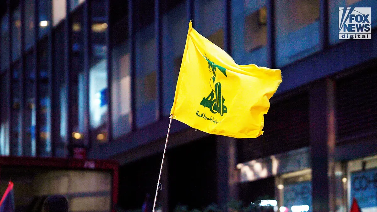 Yellow Hezbollah flag waving during an anti-Israel protest in Manhattan at night.