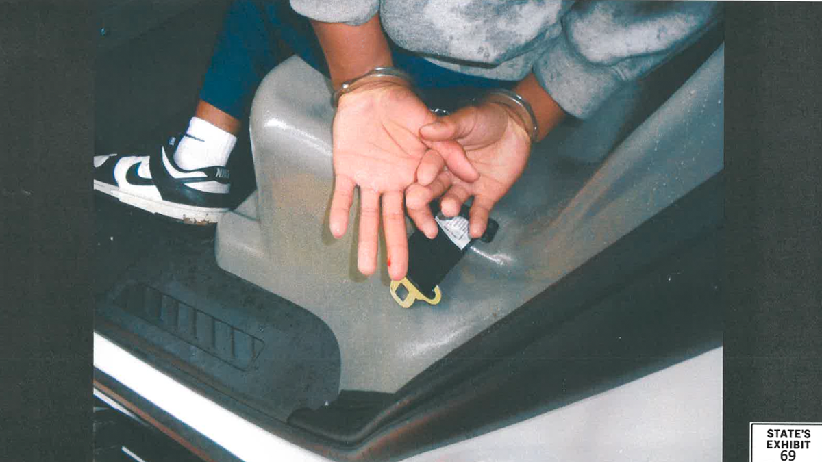 Karmelo Anthony handcuffed inside a police vehicle with blood on his left-hand finger.