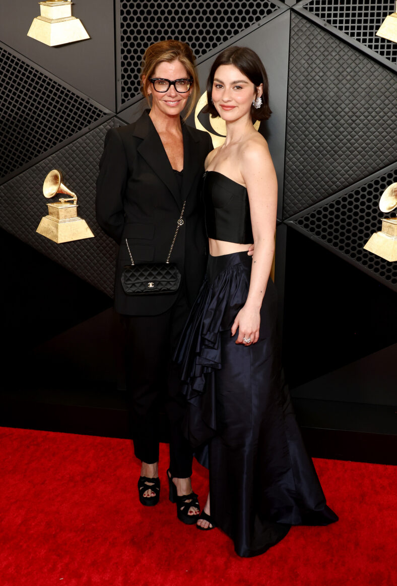 Gracie Abrams e sua mãe Katie McGrath posam juntas no tapete vermelho do Grammy, em frente ao cenário do evento.